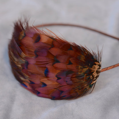 Close up of pheasant feather headpiece. Curved pheasant feathered pad on a narrow headband.