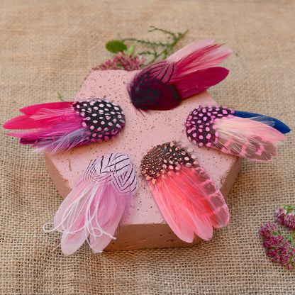 Decorative feather hair clips on a pink block with a burlap background