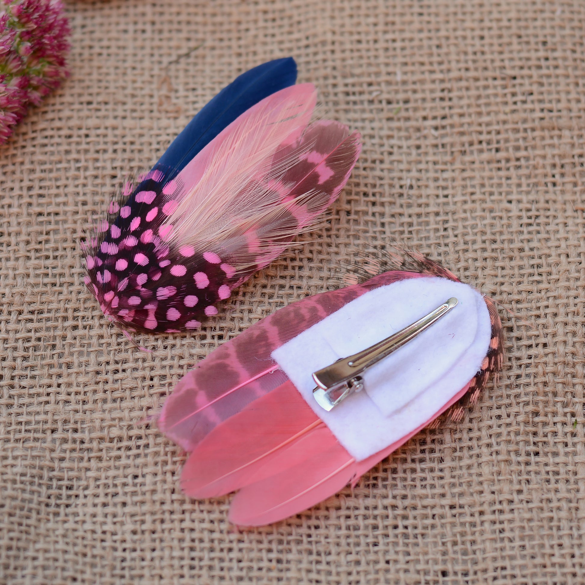 Pink feathered hair clips on a textured beige background
