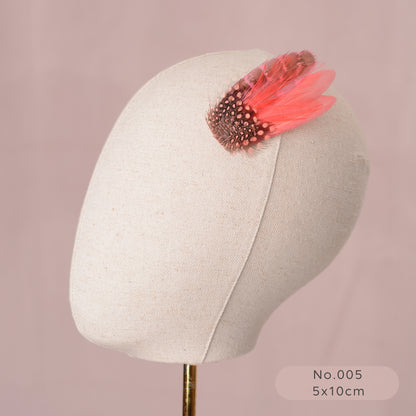 Mannequin head with a decorative coral pink feather hair clip on a pink background
