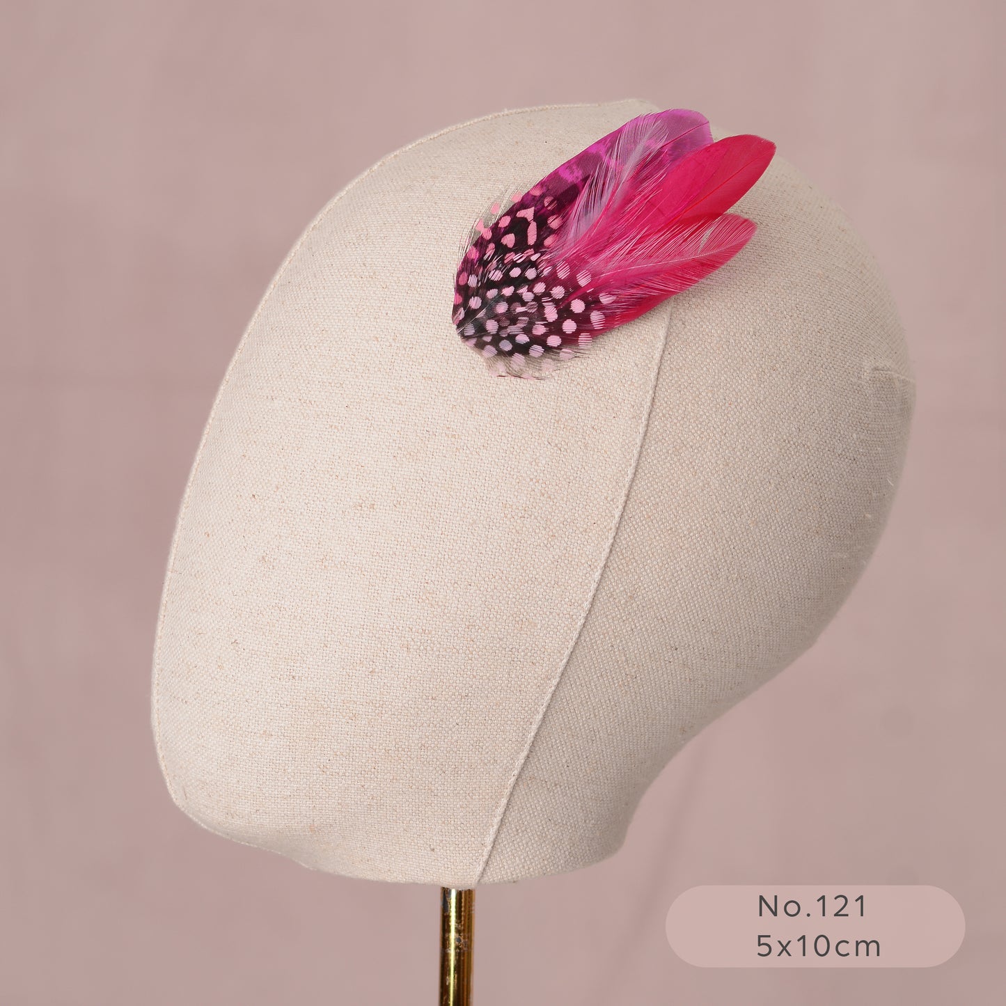 pink feather hair accessory on a mannequin head against a pink background