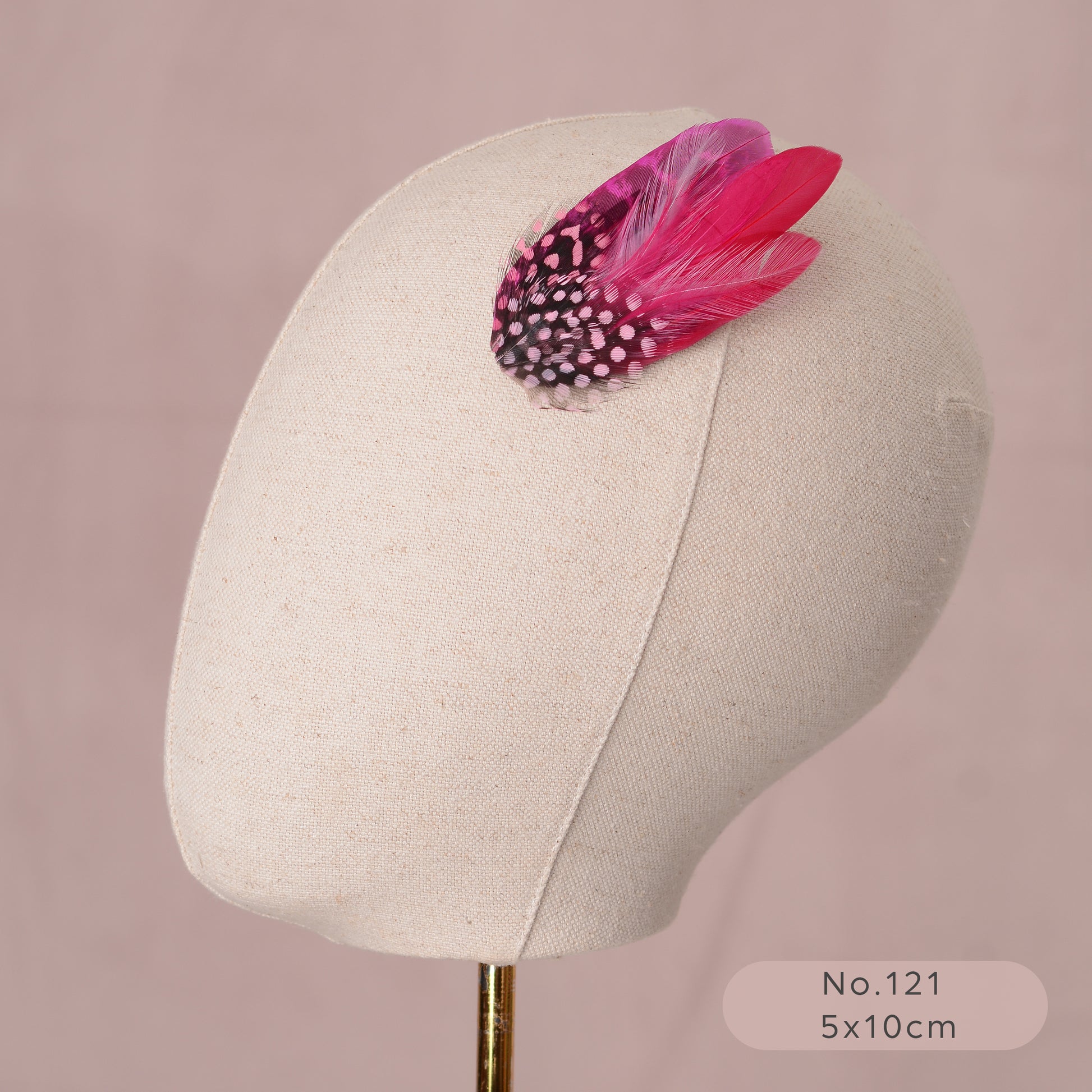 pink feather hair accessory on a mannequin head against a pink background
