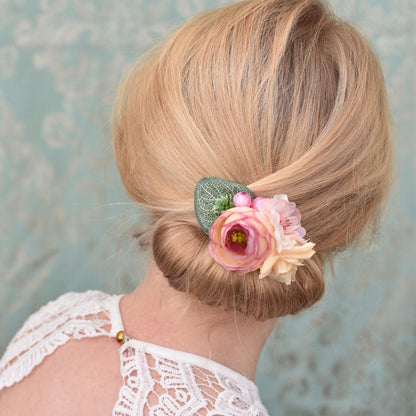 woman with blonde hair in an up-do with a decorative pink flower hair clip accessory 