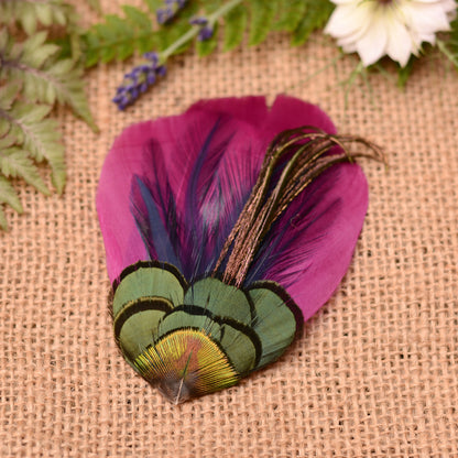 Purple feather hair clip on a textured fabric background with flowers and plants.