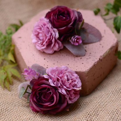 Hexagonal pink stone with purple and mauve flower hair accessories on a burlap cloth with green leaves.