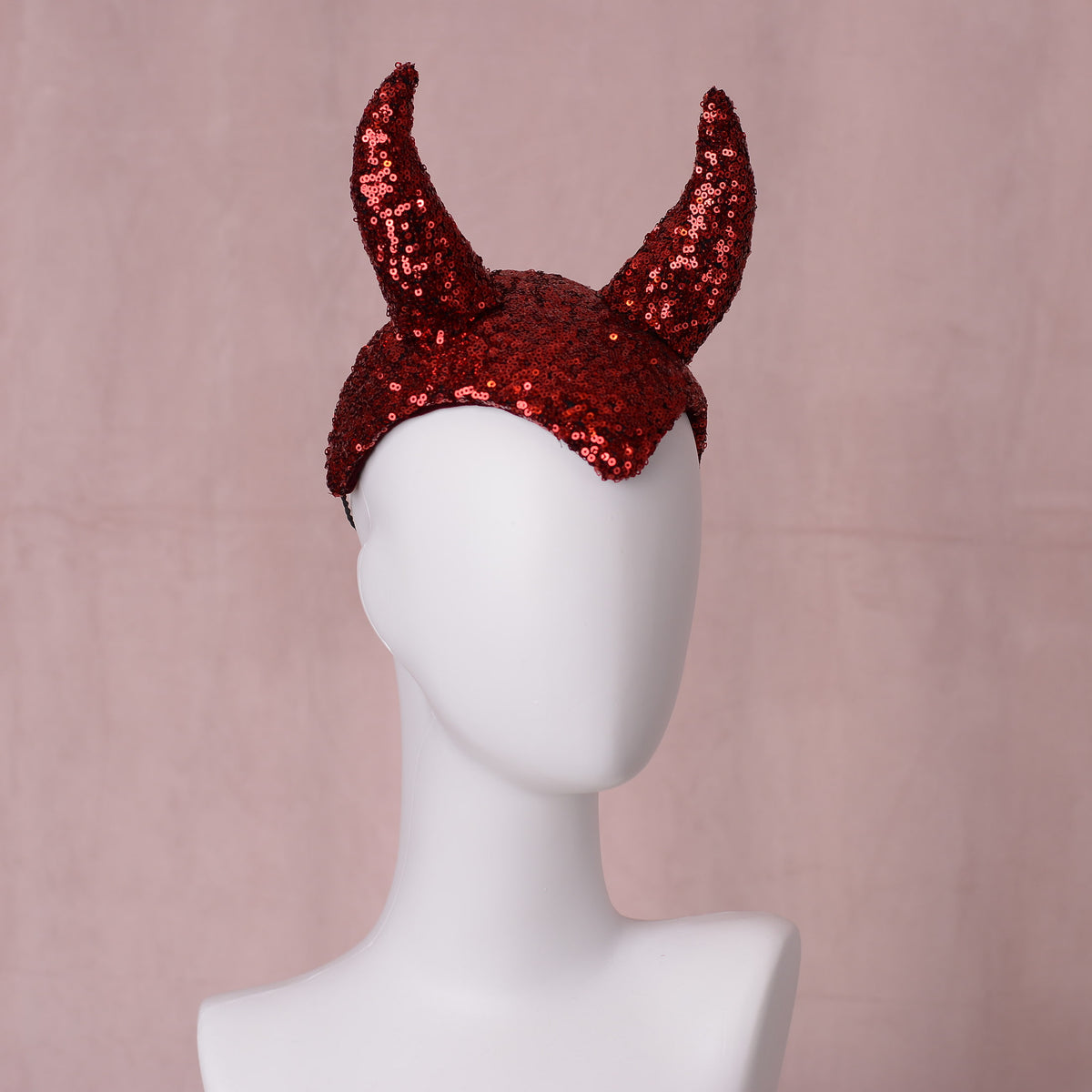 Red sequin devil horn vintage style headress displayed on a white mannequin head against a soft pink background.