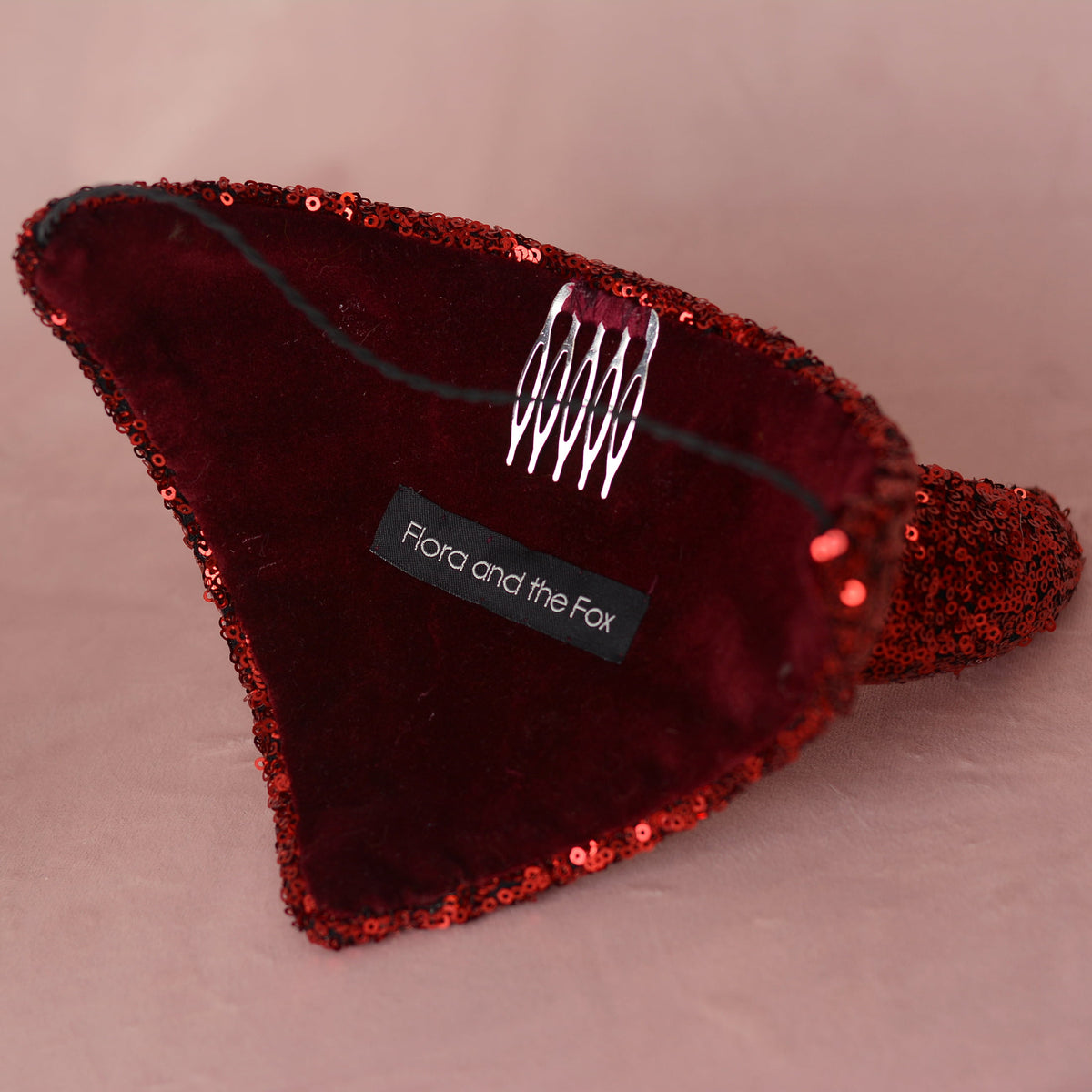 A red sequined and velvet devil headpiece by Flora and the Fox, featuring a silver metal spring clip on the inside.