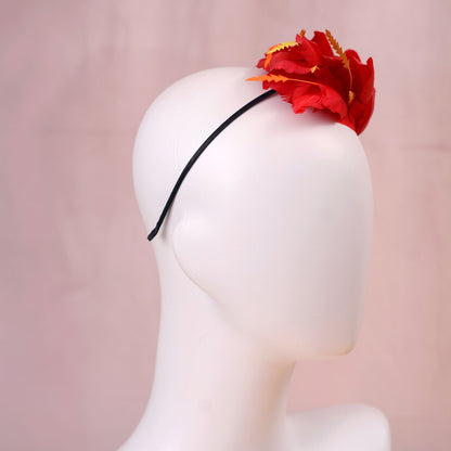 A bright red feather fascinator hat with orange-tipped feathers, displayed on a white mannequin head against a soft pink background.