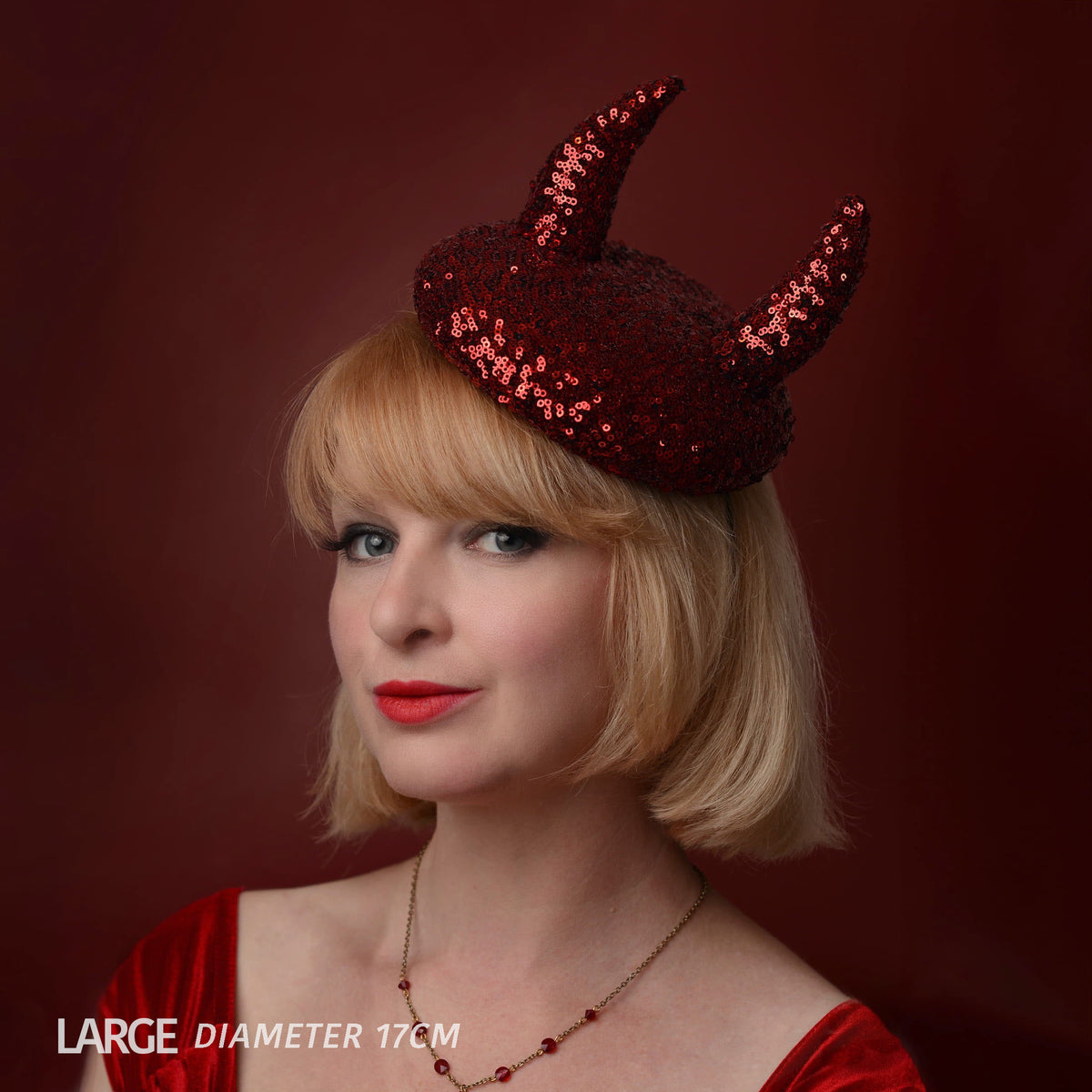 A woman with a short blonde bob wears a red sequin devil horn beret hat against a dark red background. The text 'LARGE DIAMETER 17CM' is visible in the bottom-left corner.