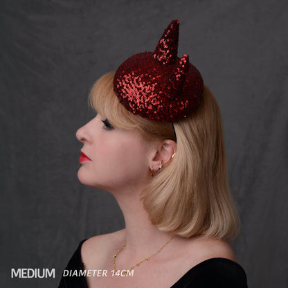 A woman in profile wearing a sparkling red sequin devil horn hat against a dark gray backdrop. The text overlay at the bottom left reads 'MEDIUM DIAMETER 14CM'.