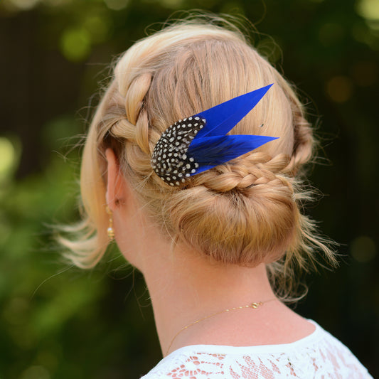 Person with braided hair and decorative feather hairpin against a blurred green background