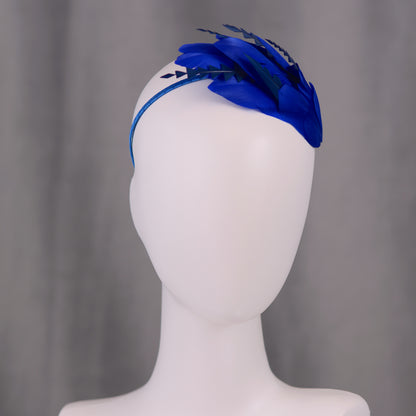 Royal blue feather wedding headband on a mannequin head against a grey background