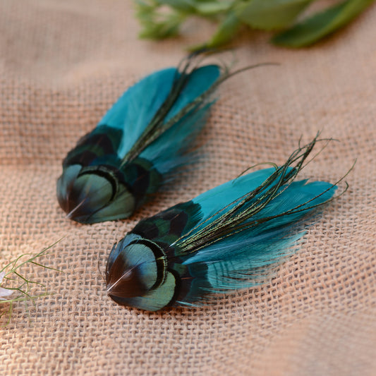 teal feather hair clips with iridescent green feathers on a burlap background with flowers