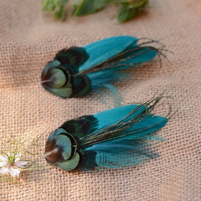 teal feather hair clip with iridescent green feathers on a burlap background with flowers