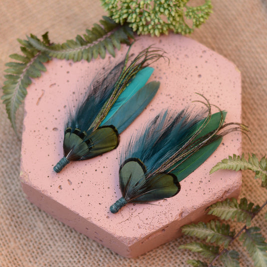Pair of teal and green feather brooch pins on pink stone