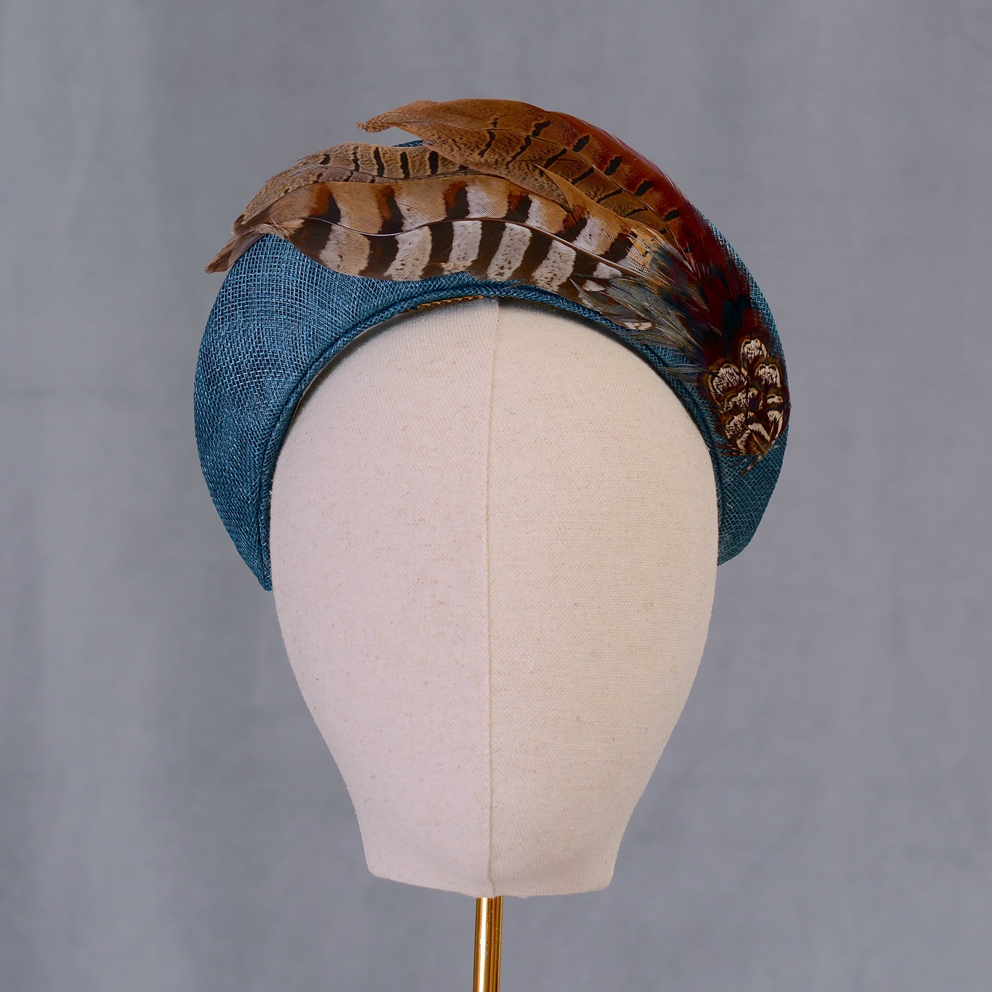 A teal turquoise bandeau style fascinator hand crafted in sinamay straw adorned wth pheasant feathers with beautiful natural markings and earthy tones. Perfect for autumn weddings, horse racing and events.