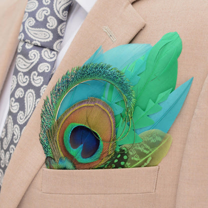 A close-up of a beige suit jacket with a white dress shirt, a grey paisley tie, and a vibrant green and turquoise  peacock feather pocket square in the breast pocket.