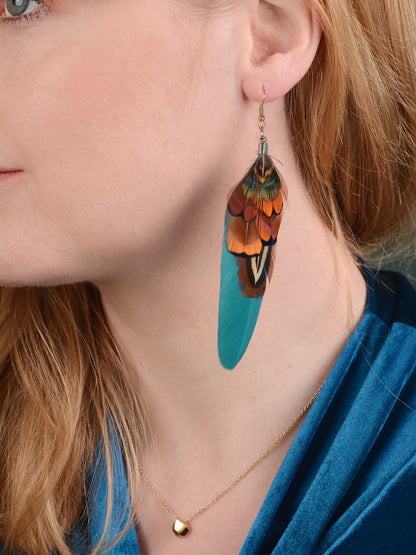 Close up of woman wearing a long feather earring in teal and pheasant feathers.